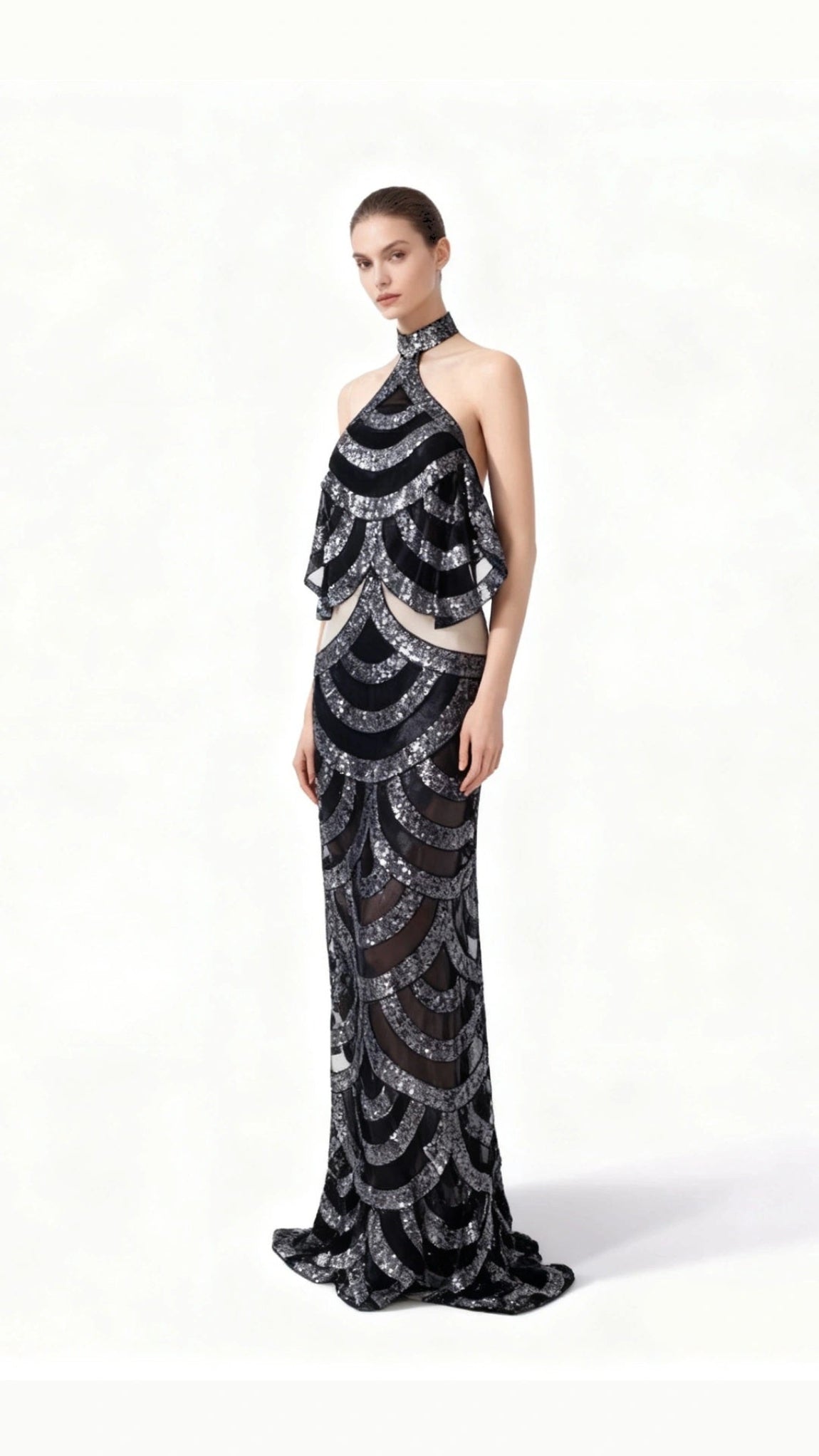 Woman wearing a black and silver patterned evening gown on a white background